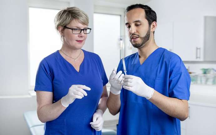 Medical staff, woman and man with plastic syringe.