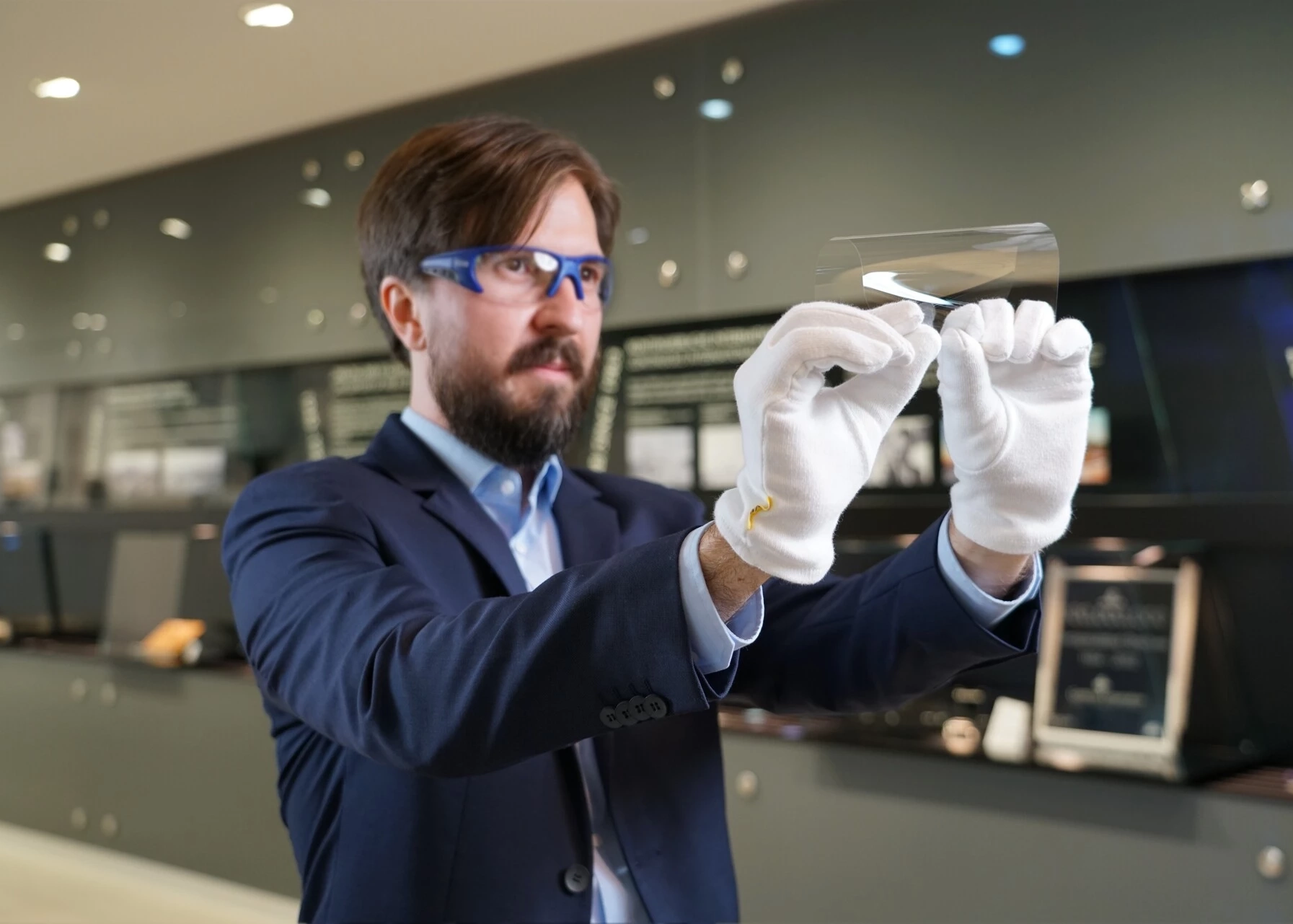 Man in blue suit demonstrates the flexibility of SCHOTT ultra-thin cover glass for smartphones