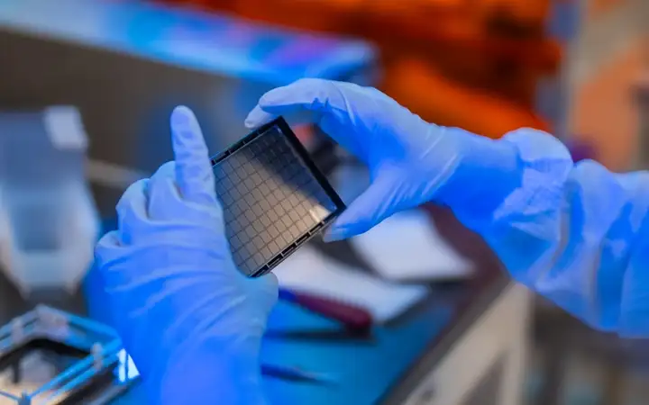 Scientist holding a 96-well chambered microarray plate.