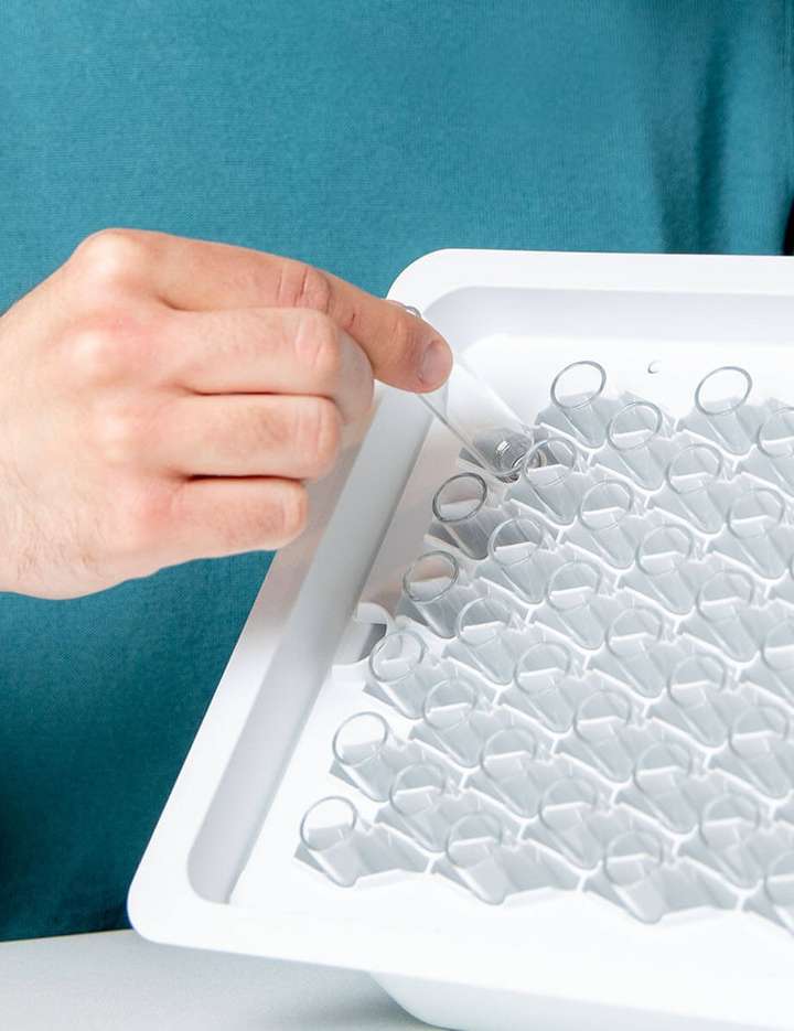 Male in green sweater holding a nest of SCHOTT Pharma’s cartriQ® Large Volume cartridges