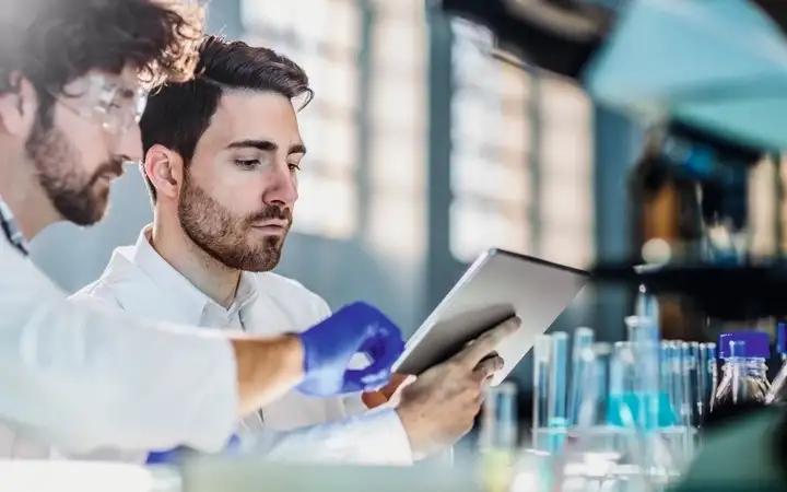 Two male scientists looking at a tablet display