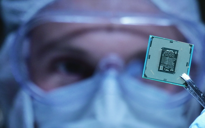 Scientist holding up a small microchip with tweezers