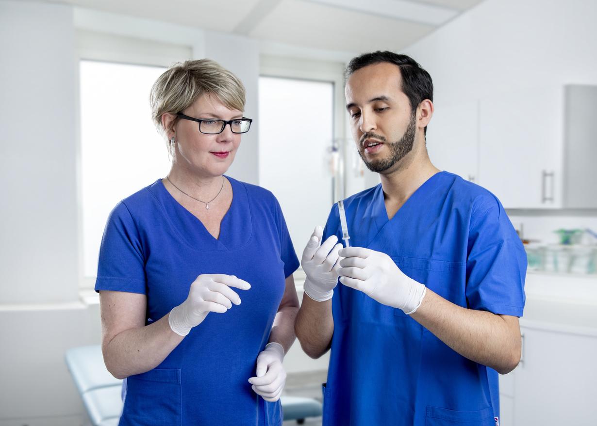 Two medical assistants preparing the syringe with the vaccine