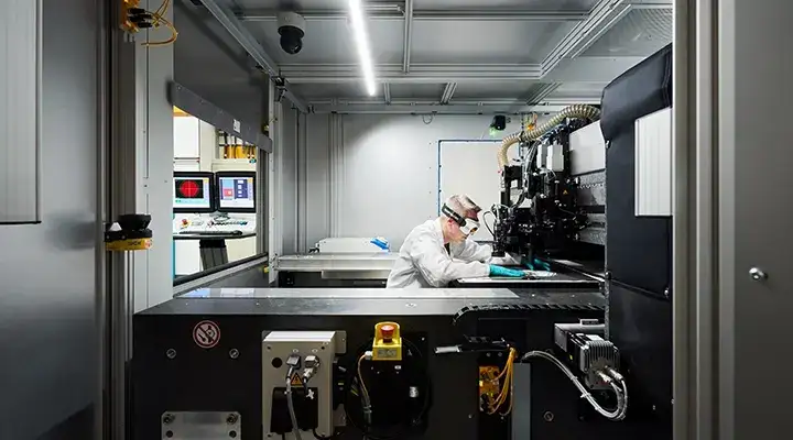 Man wearing safety goggles working on a machine in a production facility