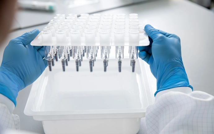 A woman holds a so-called nest with large-volume pre-fillable glass syringes with permanently integrated needles from SCHOTT Pharma in her hands.