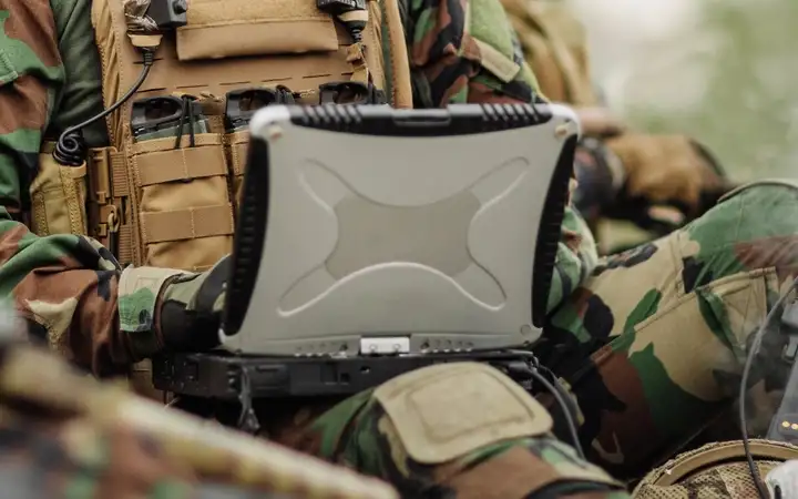 Male soldier in sunglasses looking at a laptop