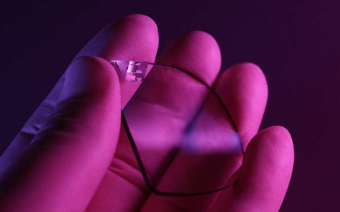 Eine Hand hält ein optisches Lichtleiterelement (LOE) für eine Augmented Reality Brille (AR)