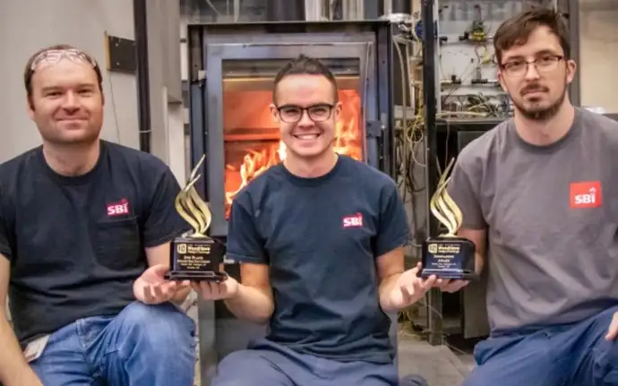 Three men kneel down in front of a wood stove