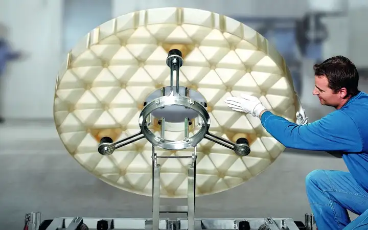 Technician working on a large mirror substrate for an observatory telescope