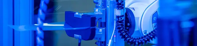 Close-up of a robotic arm with precision tool under blue lighting.