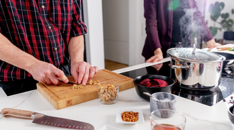 Two people cooking, man chopping walnuts