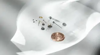 Miniaturized hermetic components next to a coin for size comparison