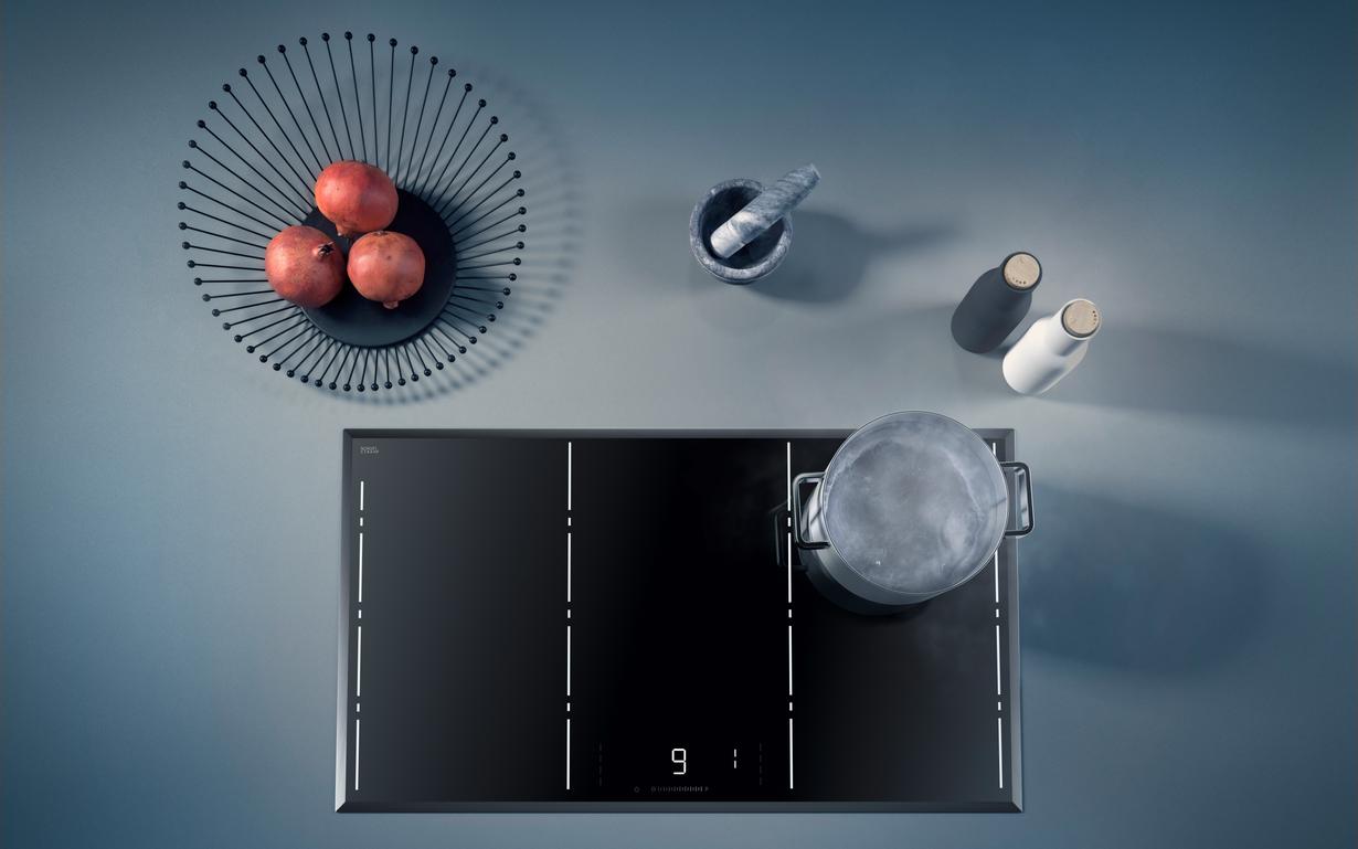 	View from above of a CERAN Luminoir™ cooktop with pot and decoration