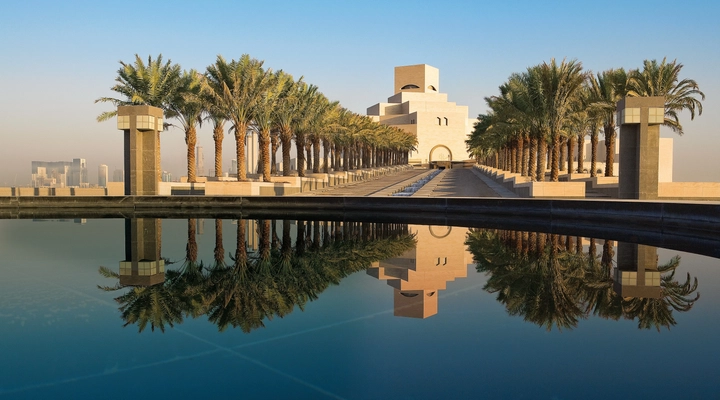 Museum of Islamic Art in Doha, Qatar through a row of palm trees