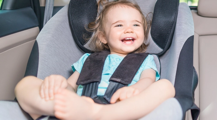 Small baby in a child seat in the back of a luxury vehicle