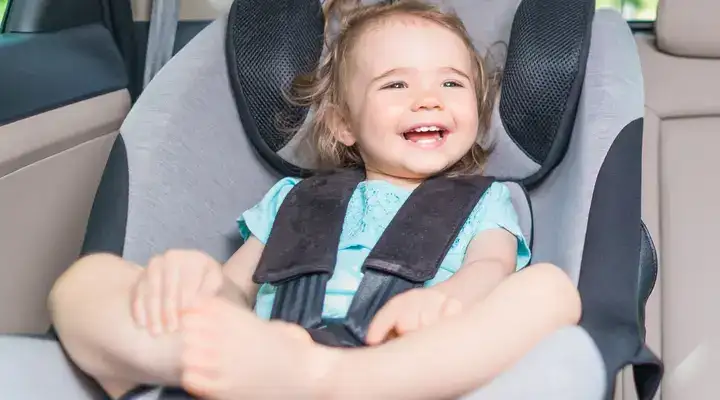 Small baby in a child seat in the back of a luxury vehicle