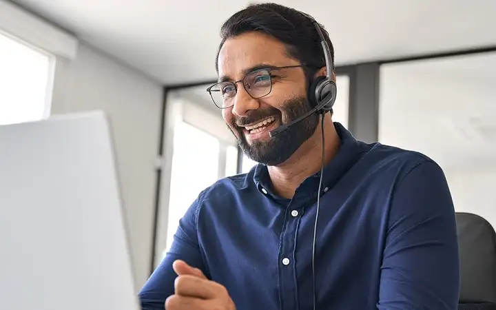 Man with headset participates in a Pharmaversity® Academy session from home with his laptop