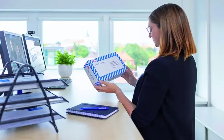 A woman in an office holding and inspecting a package