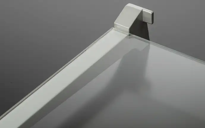 Close-up of a glass refrigerator glass shelf with metal trim and support bracket.
