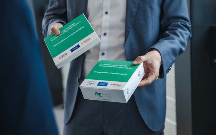 Man in business clothes holding two packs of syringes without blister packaging.