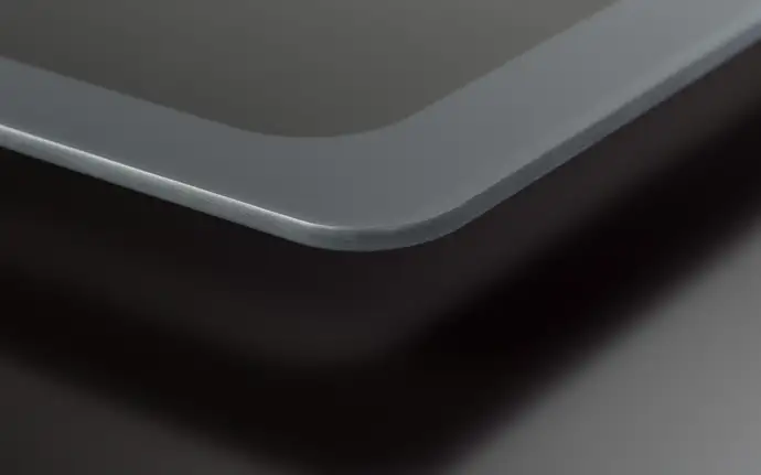 Close-up view of the rounded corner of a sleek, modern washing machine glass with  a smooth, matt surface.