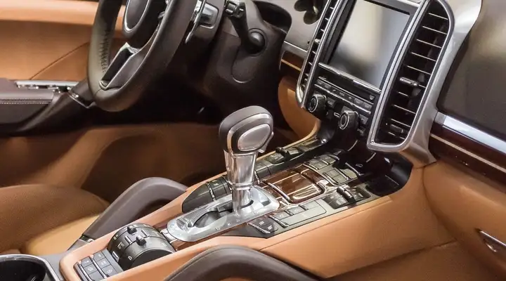 Brown interior of a luxury vehicle with dashboard, steering column and gear stick