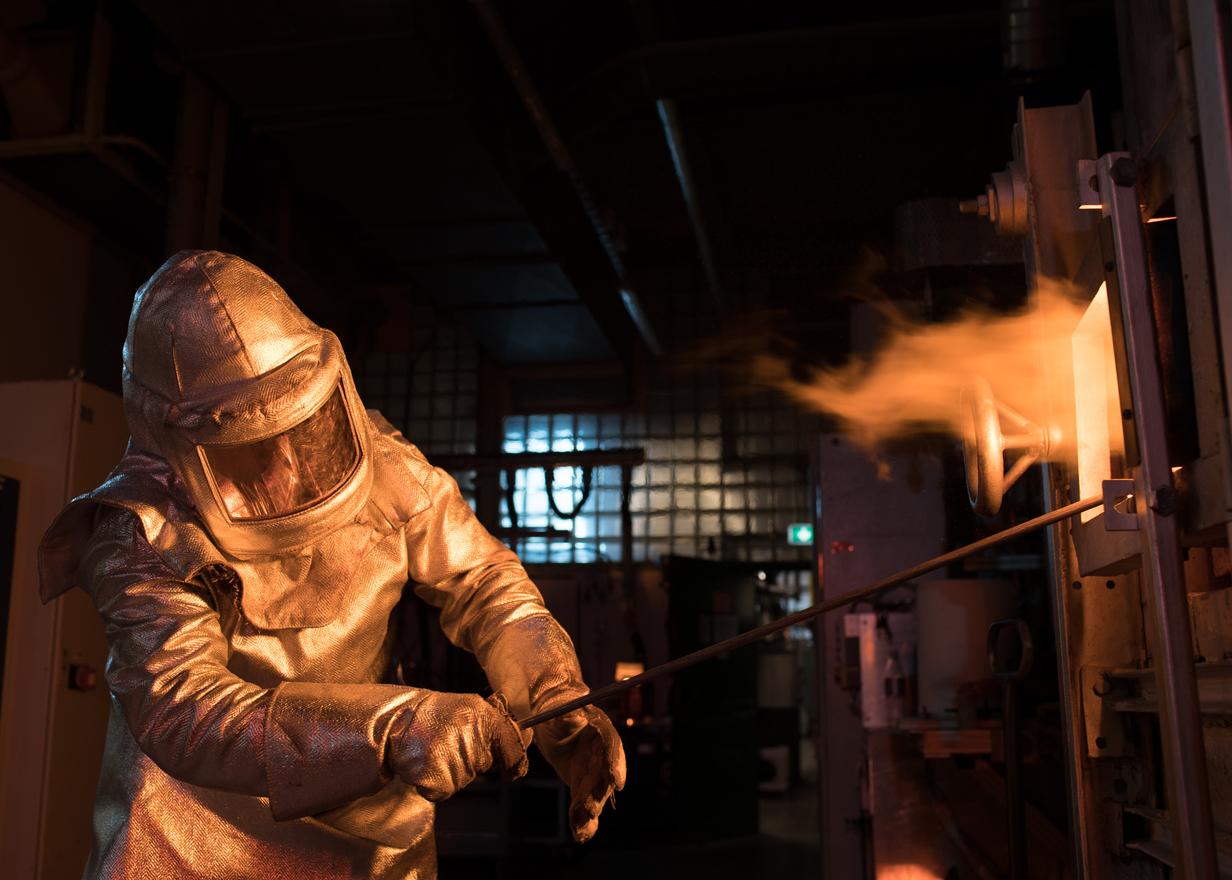 Man in protective clothing works on a glass melting tank
