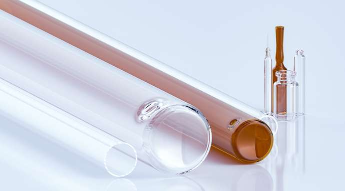 	 Close-up of glass tubes and ampoules with clear and amber liquid on a reflective surface.