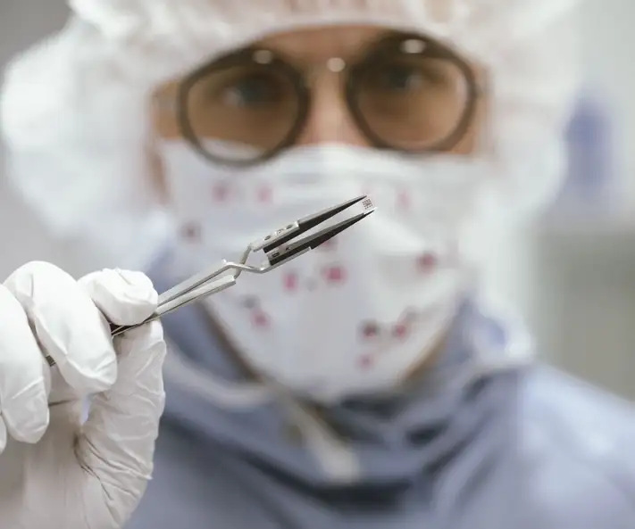 Laborangestellte hält ein miniaturisiertes medizinisches Implantat mit einer Pinzette