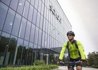迈克尔·哈恩 (Michael Hahn) 身穿亮绿色夹克骑自行车抵达美因茨的肖特办公楼