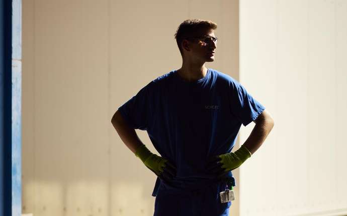 Full-body shot of a SCHOTT production worker in blue work attire