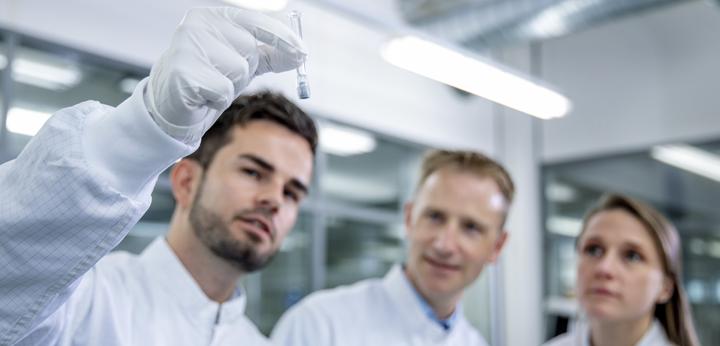 Group of lab workers looking at syringe for visual inspection check