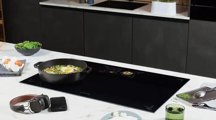 SCHOTT CERAN® Luminoir™ TFT cooktop with a pan, digital recipe display, and prepared ingredients.
