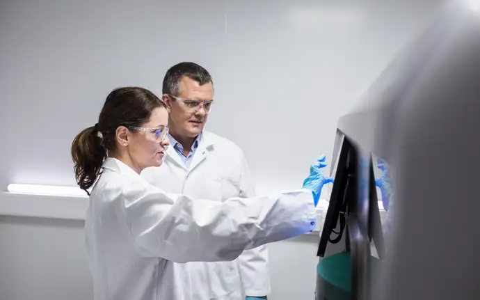 Two scientists operate diagnostic equipment in a laboratory