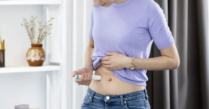 Women sitting in living room injecting drug via large-volume autoinjector.