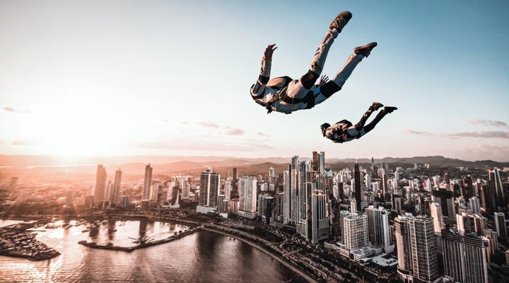 Two skydivers freefall over a city