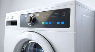 A close-up view of a modern front-loading washing machine. The image focuses on the control panel made of glass,  which features a large central dial and several illuminated buttons in green and blue. The door of the washing machine is partially visible at the bottom.