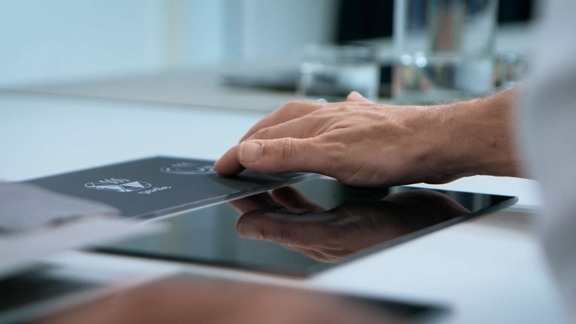 Hand touching glass panel in modern kitchen demonstrating haptic feedback