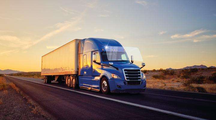 Truck driving down country road at sunset