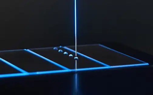 Single glass substrate on contact angle drop test instrument with multiple drops in a row.
