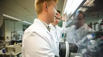 Nicolas watching Pirmin preparing glass-ceramic powder in the lab at SCHOTT