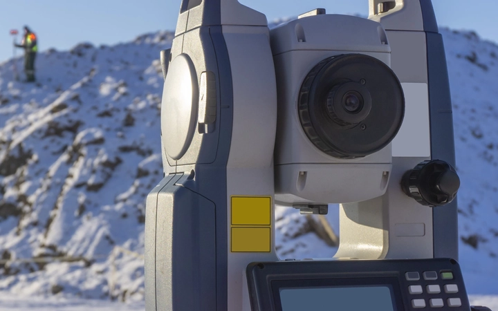 Laser rangefinding equipment pointing towards a man on a snow-covered hill