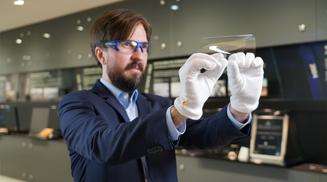 Scientist with gloves bends wafer-thin glass