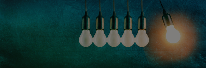 One lit bulb next to four unlit bulbs on a blue-green background.