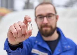 Marius Amschler stands in front of a cullet warehouse and holds a vial up to the camera