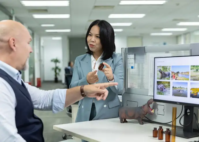 Jocelyn Jiang und Dr. Folker are in the office next to a desk, talking while Dr. Folker Steden points at his computer screen