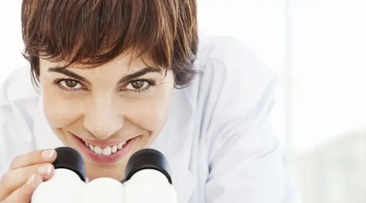 Female scientist looking up from a microscope