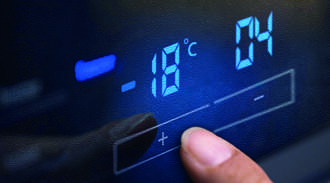Finger touching a glass control panel with blue display