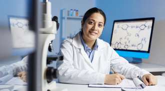 A scientist sits at a table and writes on a clipboard