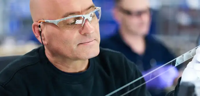 Technician inspecting glass substrate in laboratory setting